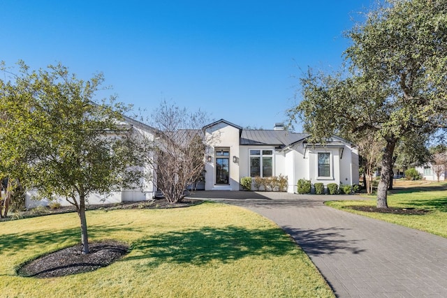 view of front of home with a standing seam roof, metal roof, decorative driveway, and a front yard