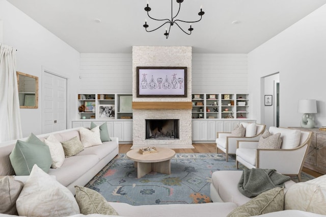 living area featuring light wood-type flooring, an inviting chandelier, and a stone fireplace