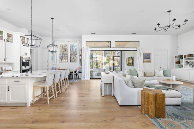 living room with visible vents, light wood-type flooring, and a chandelier