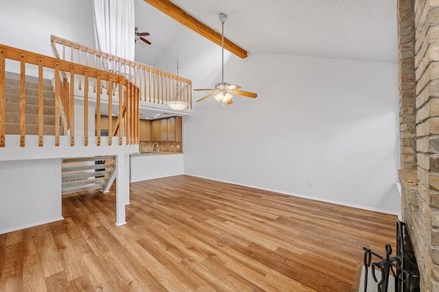 unfurnished living room featuring beam ceiling, stairway, ceiling fan, wood finished floors, and high vaulted ceiling