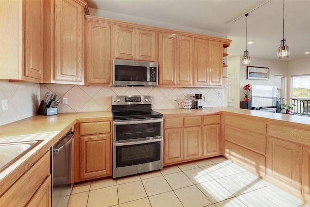 kitchen featuring tasteful backsplash, hanging light fixtures, stainless steel appliances, light countertops, and light brown cabinetry