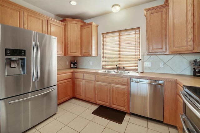 kitchen with stainless steel appliances, light countertops, a sink, and light tile patterned flooring