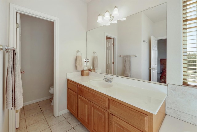 bathroom with toilet, tile patterned flooring, baseboards, and vanity