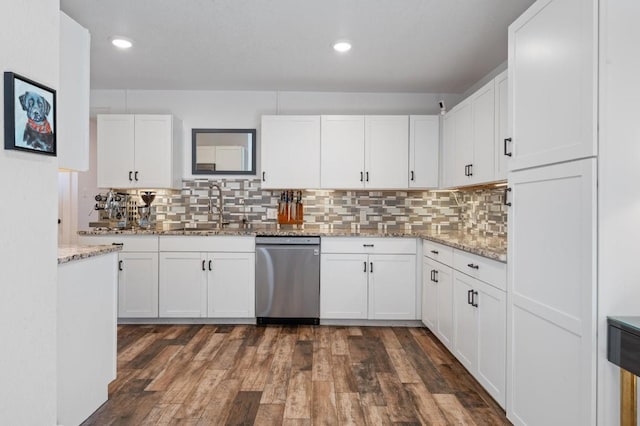 kitchen with stainless steel dishwasher, dark wood-style flooring, a sink, and white cabinetry