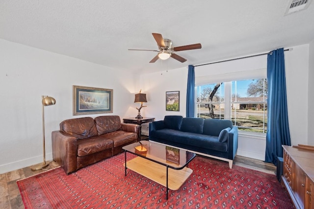 living room with baseboards, visible vents, ceiling fan, and wood finished floors