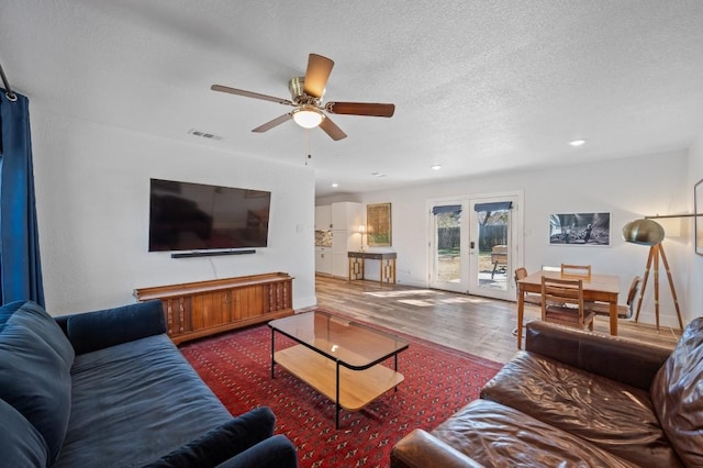 living area with french doors, visible vents, ceiling fan, a textured ceiling, and wood finished floors