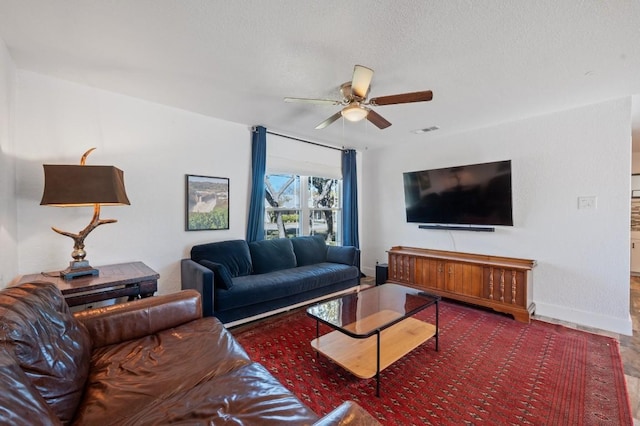 living area with ceiling fan, a textured ceiling, visible vents, and baseboards