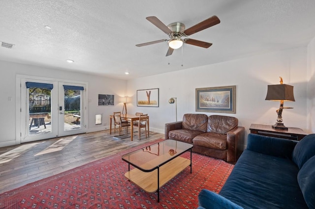 living room featuring baseboards, wood finished floors, a textured ceiling, french doors, and recessed lighting