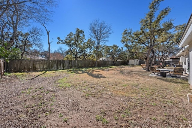 view of yard featuring a fenced backyard, a storage unit, and an outbuilding