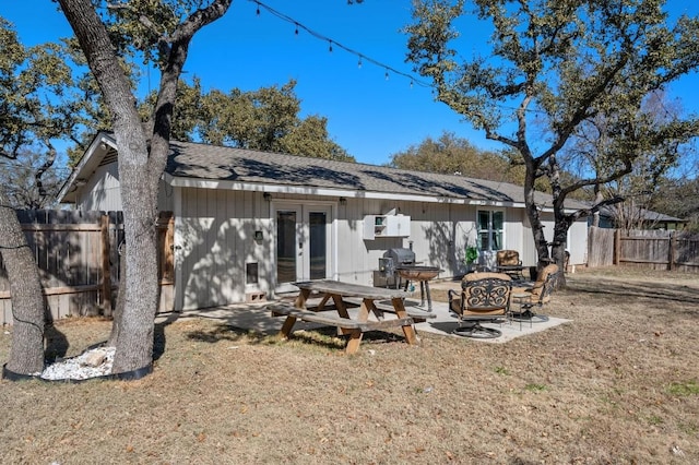 rear view of house with a patio, french doors, a shingled roof, and fence