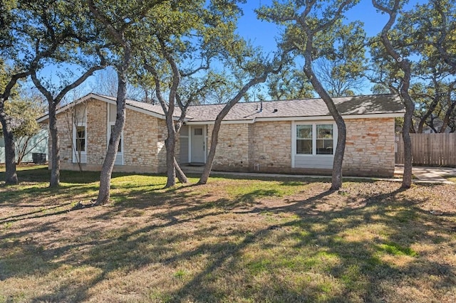 view of front facade with stone siding, fence, and a front yard