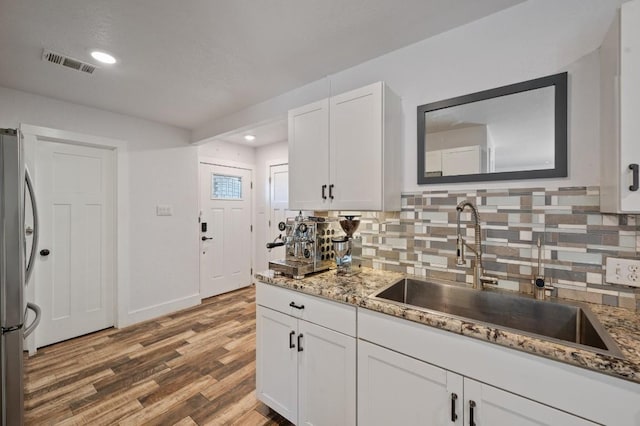 712 Ruby Isle Dr, Leander, TX 78641 - kitchen featuring freestanding refrigerator, tasteful backsplash, white cabinets, wood finished floors, and light stone countertops