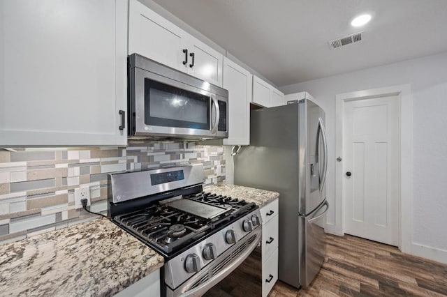 712 Ruby Isle Dr, Leander, TX 78641 - kitchen featuring appliances with stainless steel finishes, tasteful backsplash, white cabinetry, and light stone countertops