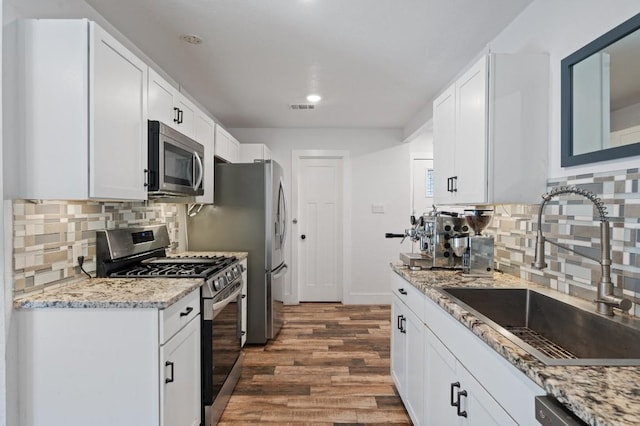 712 Ruby Isle Dr, Leander, TX 78641 - kitchen with appliances with stainless steel finishes, dark wood finished floors, tasteful backsplash, recessed lighting, and white cabinets