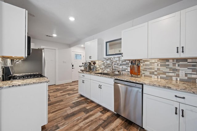 kitchen with stainless steel appliances, backsplash, a sink, and dark wood finished floors