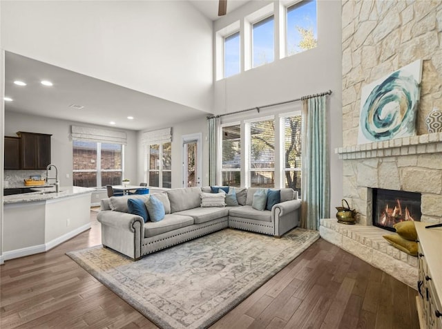 living area with recessed lighting, dark wood-style flooring, and a stone fireplace