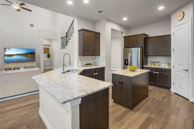 kitchen with a sink, visible vents, open floor plan, dark brown cabinets, and stainless steel fridge with ice dispenser