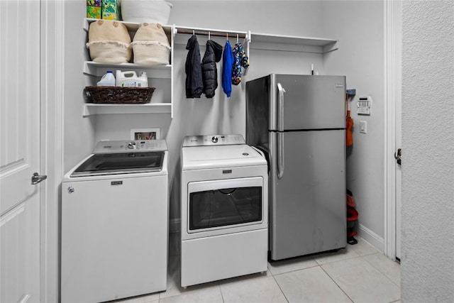 laundry area with light tile patterned floors, laundry area, washer and clothes dryer, and baseboards