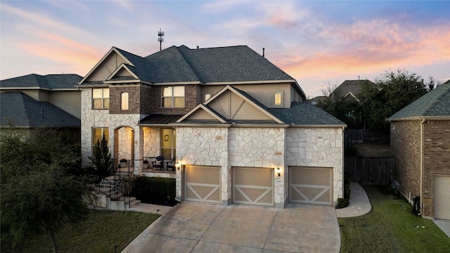 view of front of home with a garage, concrete driveway, roof with shingles, and stone siding