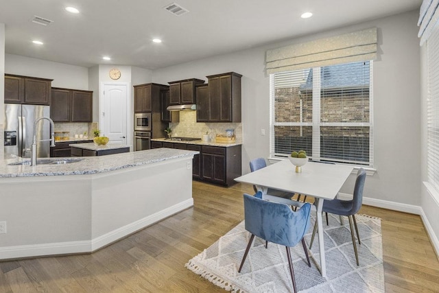 kitchen featuring appliances with stainless steel finishes, a center island, visible vents, and dark brown cabinetry