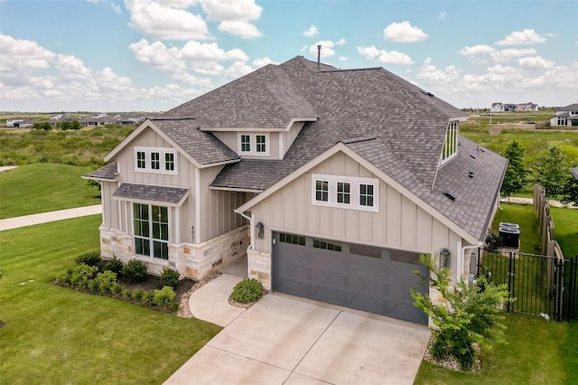 view of front facade with a garage, a shingled roof, fence, a front lawn, and board and batten siding