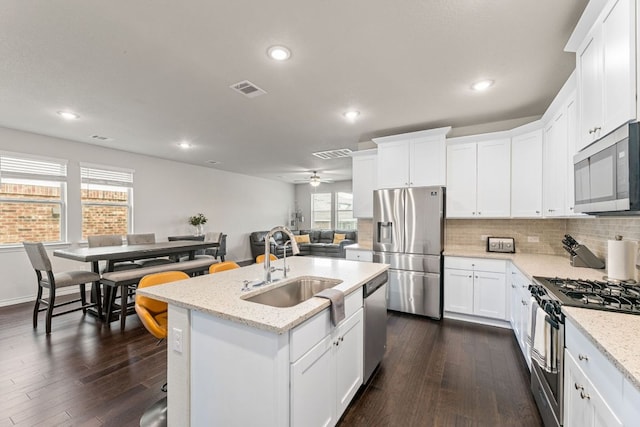 kitchen with dark wood-style flooring, visible vents, decorative backsplash, appliances with stainless steel finishes, and a sink