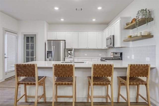 kitchen featuring stainless steel appliances, a sink, visible vents, white cabinetry, and light countertops