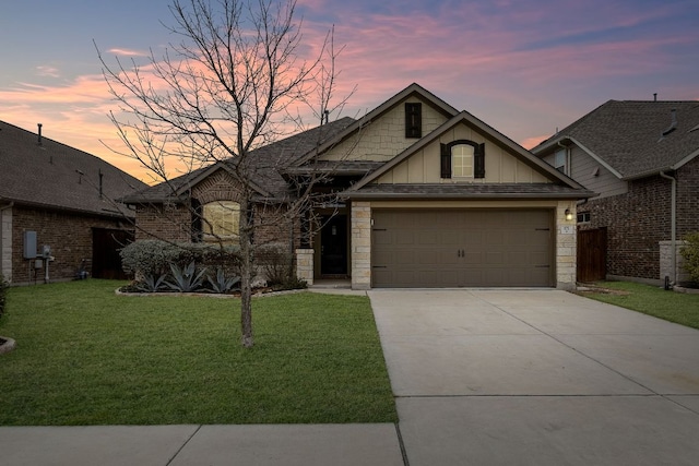 view of front of home featuring a yard, concrete driveway, board and batten siding, a garage, and stone siding