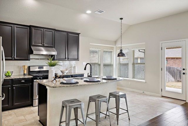 kitchen featuring stainless steel gas range oven, visible vents, a sink, under cabinet range hood, and backsplash