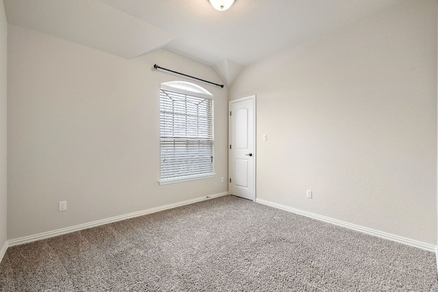 carpeted empty room featuring lofted ceiling and baseboards