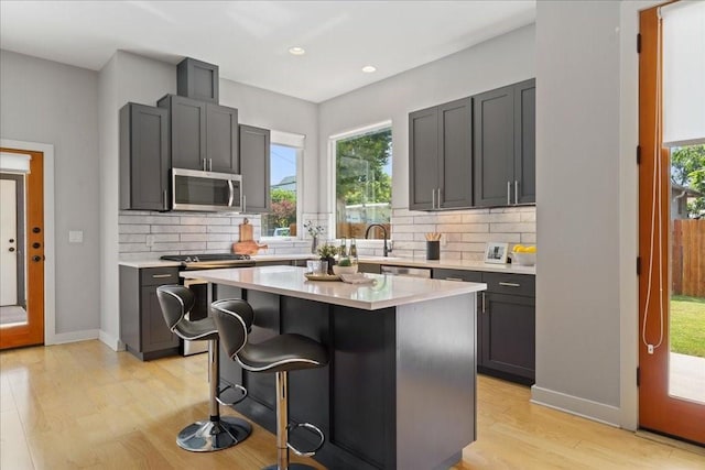 kitchen with a kitchen breakfast bar, light countertops, appliances with stainless steel finishes, and light wood-style floors