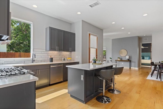 kitchen with light wood-style floors, light countertops, a sink, and stainless steel dishwasher