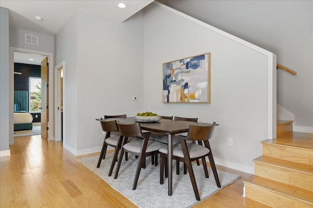 dining space with visible vents, stairway, baseboards, and wood finished floors