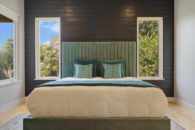 bedroom with wooden walls, baseboards, and wood finished floors