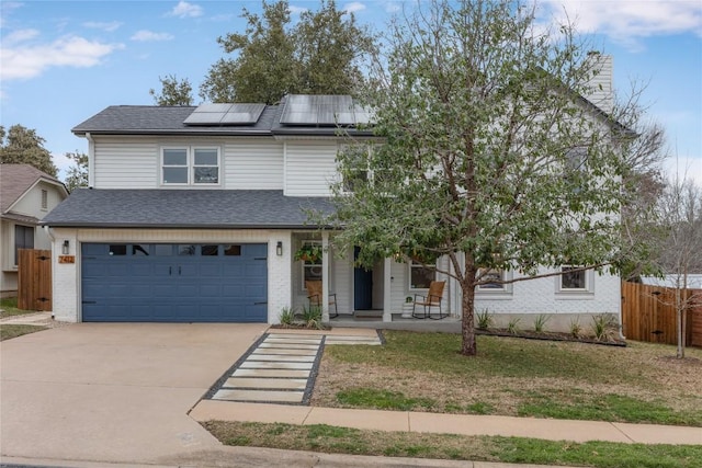 view of front facade featuring a porch, an attached garage, solar panels, fence, and concrete driveway