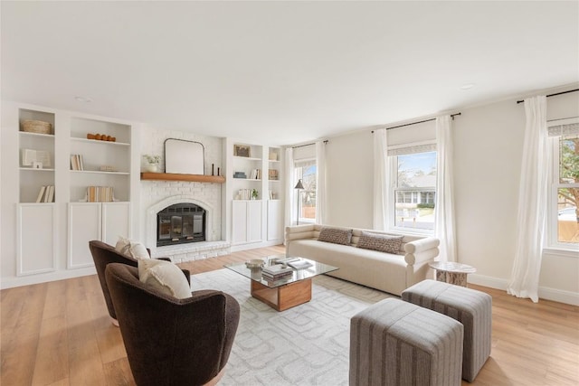 living room featuring light wood-style floors, a healthy amount of sunlight, a fireplace, and baseboards