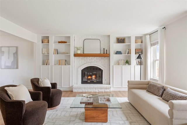 living area featuring a brick fireplace, wood finished floors, and built in features