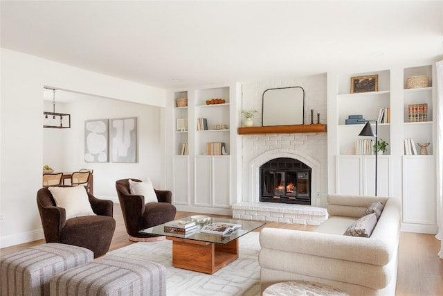 living room featuring baseboards, a fireplace, built in features, and wood finished floors