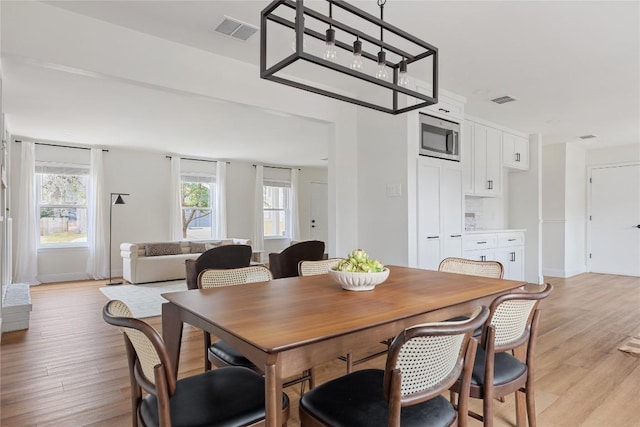 dining area featuring visible vents, light wood-style flooring, and a wealth of natural light