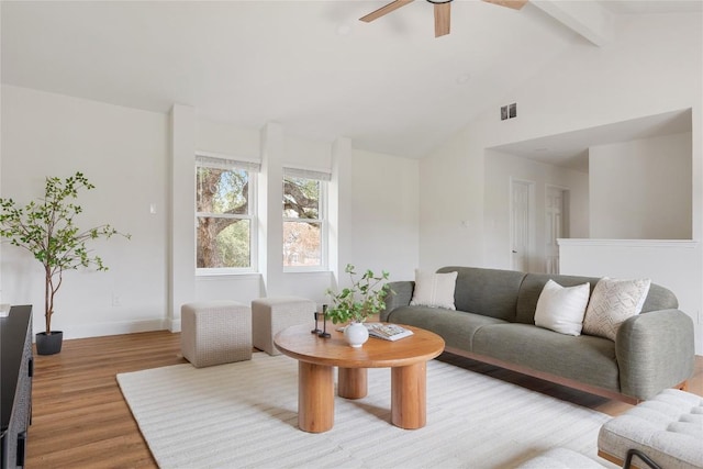 living room featuring visible vents, baseboards, a ceiling fan, vaulted ceiling with beams, and light wood-style floors