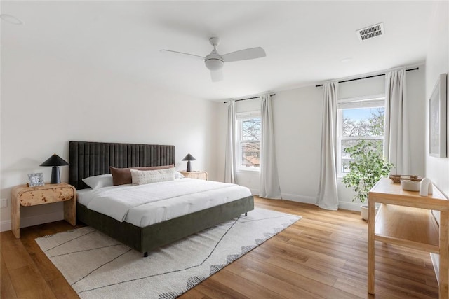 bedroom with visible vents, baseboards, light wood-style flooring, and a ceiling fan