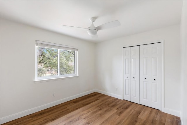 unfurnished bedroom featuring ceiling fan, a closet, wood finished floors, and baseboards