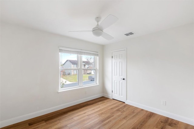 empty room with light wood-style flooring, visible vents, baseboards, and a ceiling fan