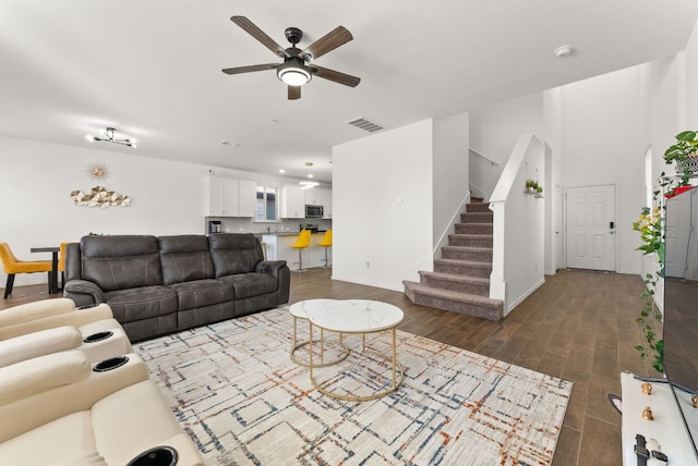 living area featuring wood finished floors, visible vents, baseboards, stairs, and a ceiling fan