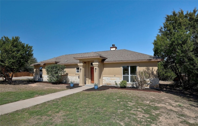 view of front of home featuring stone siding, a chimney, roof with shingles, a front lawn, and stucco siding