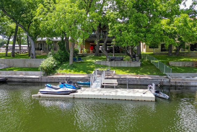 view of dock with a lawn, a water view, and fence