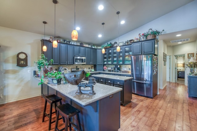 kitchen featuring a peninsula, appliances with stainless steel finishes, vaulted ceiling, and backsplash