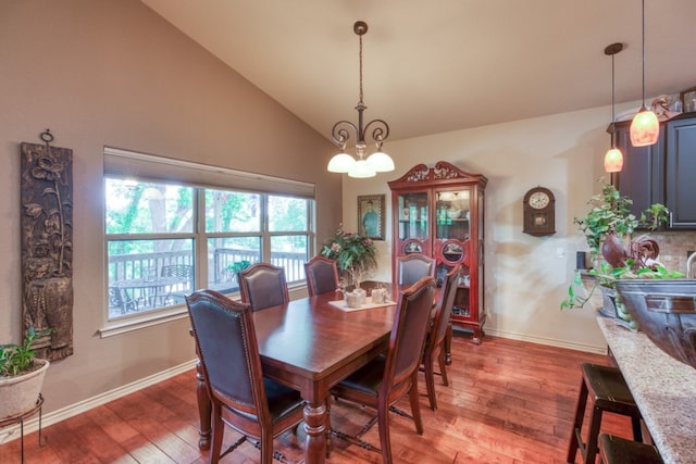 dining space featuring light wood finished floors, baseboards, a chandelier, and vaulted ceiling