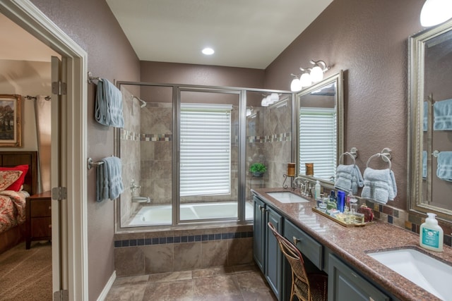 full bath with a textured wall, a sink, tiled shower / bath, and double vanity