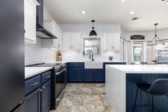 kitchen with visible vents, appliances with stainless steel finishes, blue cabinets, wall chimney range hood, and a sink